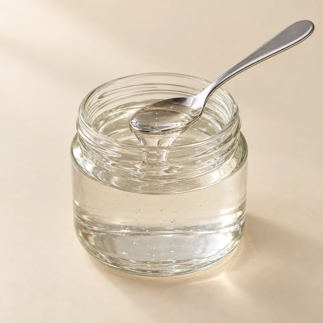 Eigene Illustration: Heller dickflüssiger Glukosesirup in einem unmarkierten Glas